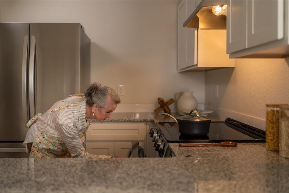 Grandma Oven Comp Photo of a woman baking in her Origins home by Betenbough Homes, West Texas' #1 home builder.