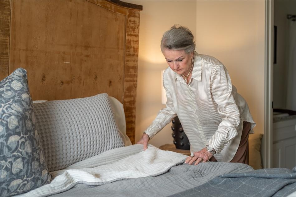 Making Bed Comp Photo of a retired woman making the bed in her downsized Betenbough home.