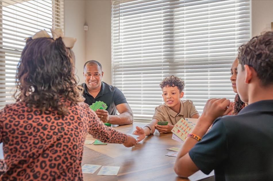Residents Comp Photo of a family playing a game at the dining table in their Betenbough home.