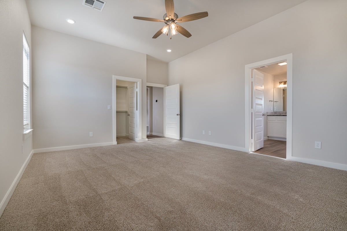 Photo of a bedroom with a view into a walk-in closet and bathroom in the Layla