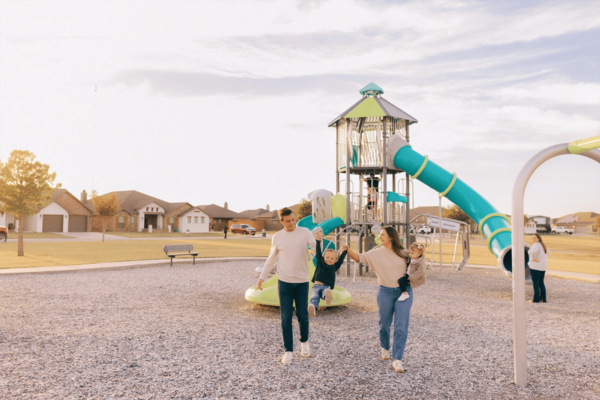 Photo of a mom and dad playing with their son and daughter at a park in Upland Crossing.