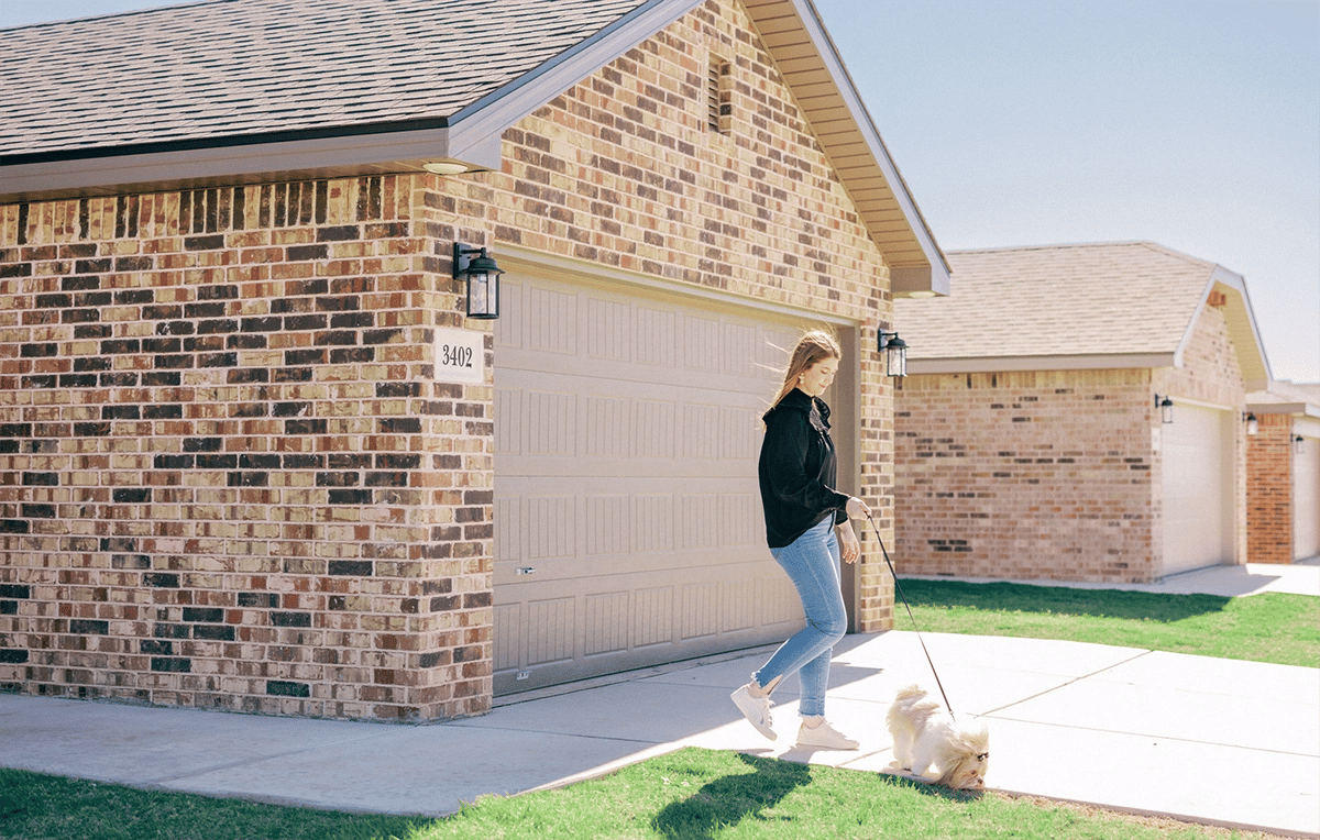 Photo of a woman walking her dog outside her Betenbough home. Betenbough Homes is one of several new home builders in Lubbock Tx.