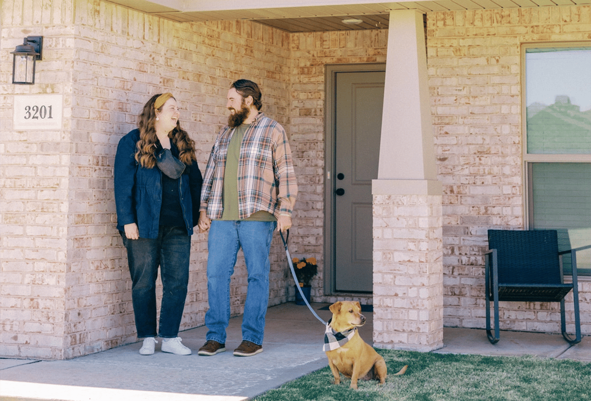 Couple with their dog standing in front of their new Betenbough home