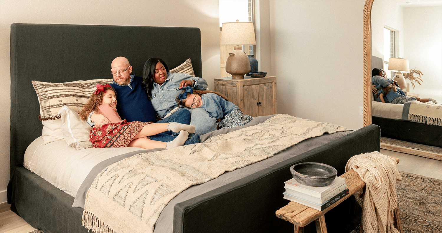 Photo of a family snuggling in their bed in the master bedroom of their Betenbough home. Betenbough Homes is one of several new home builders in Lubbock Tx.