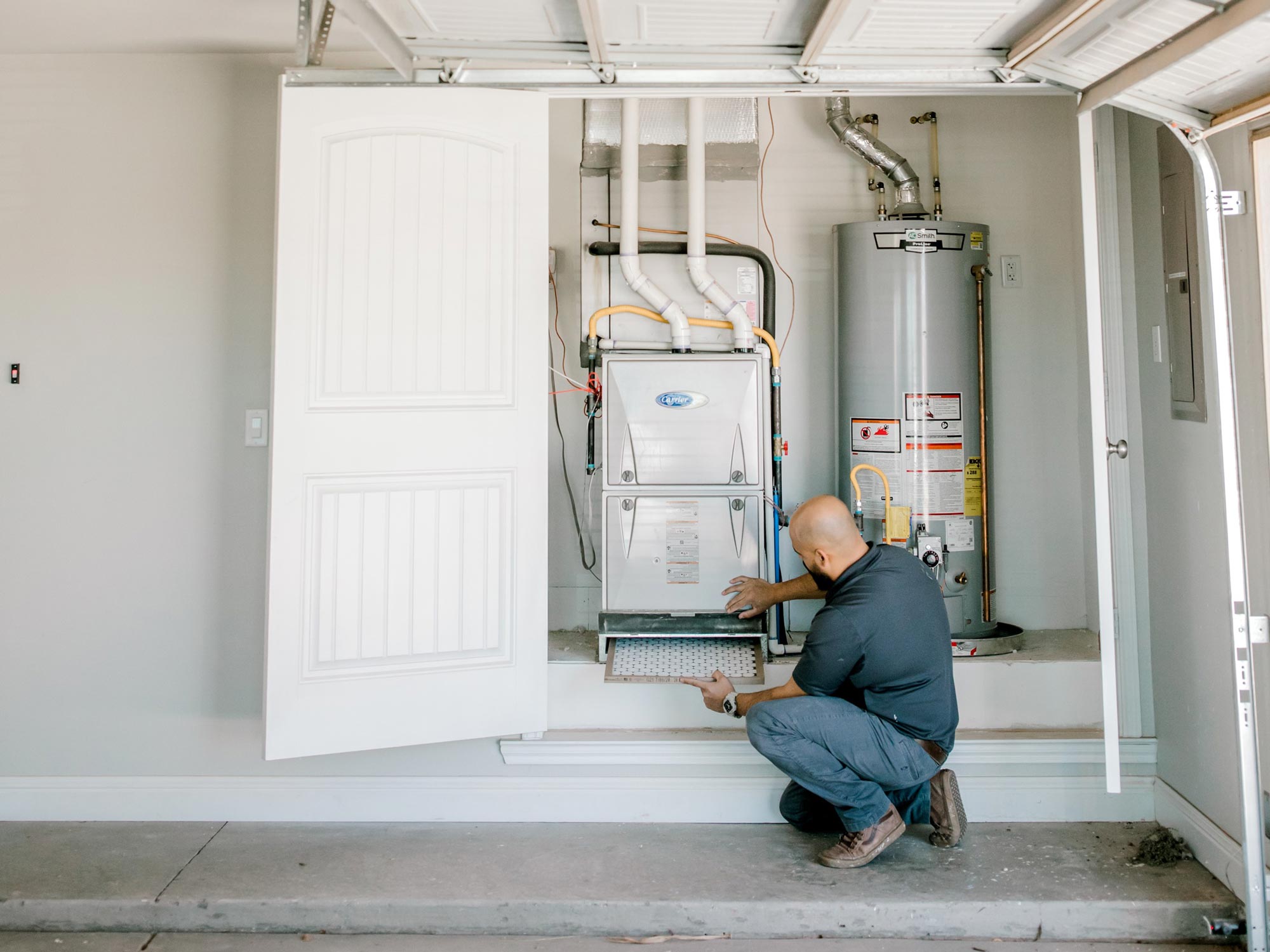 Photo of a man changing an air filter on a Betenbough home.