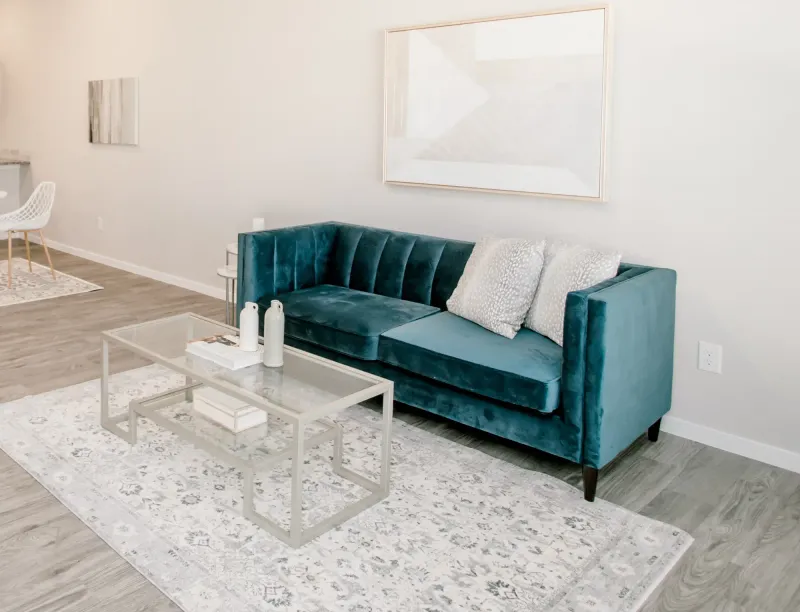 Photo of a turquoise velvet couch and other furnishings in a Betenbough home living room.