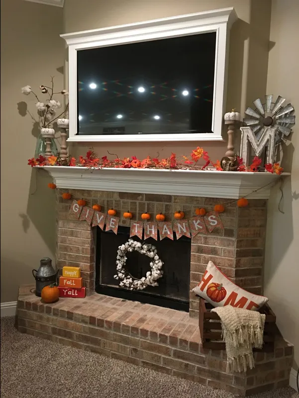 Photo of a Betenbough home mantle and hearth decorated with fall leaves, cotton stalks, mini pumpkins, a