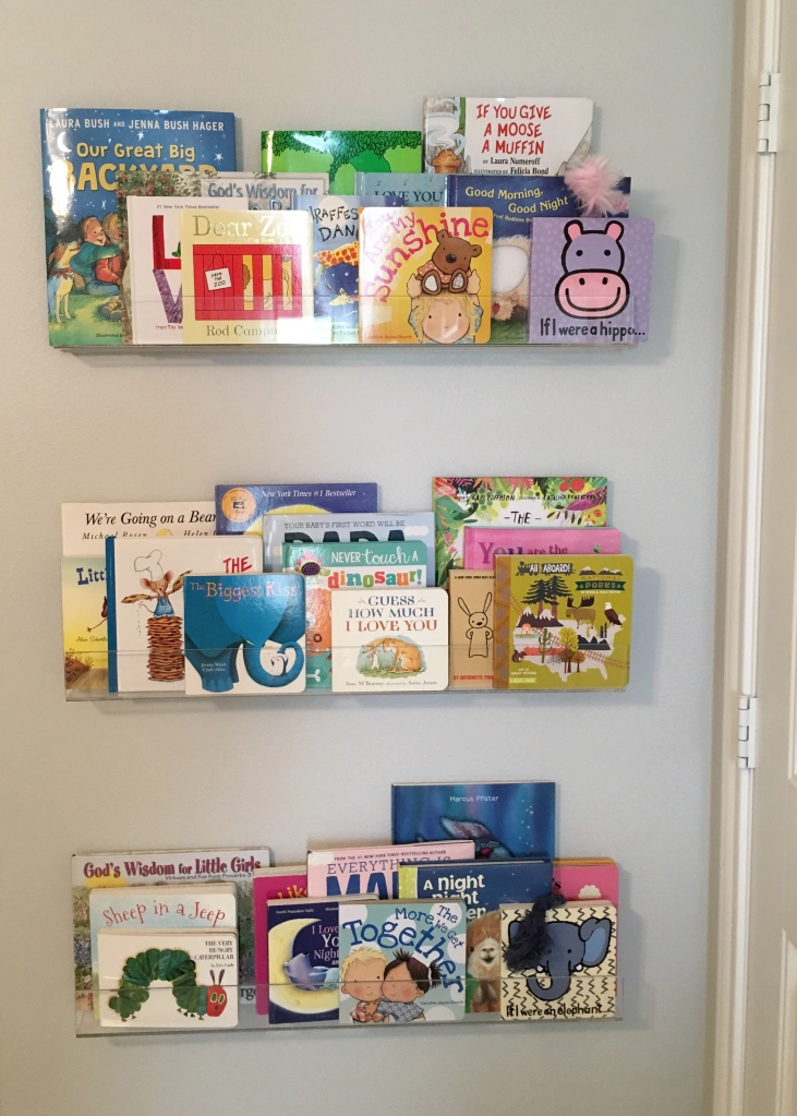 Photo of baby books organized on acrylic shelves.