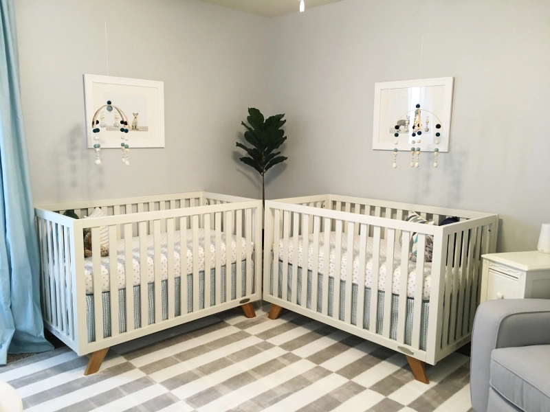 Photo of a twin nursery with cribs arranged to meet in a corner of the room.