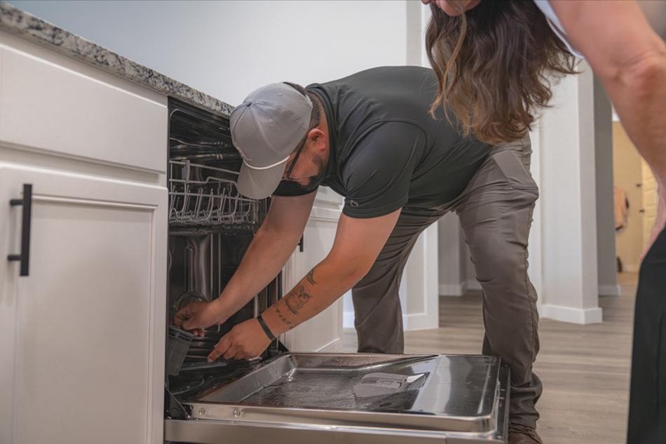 A Betenbough Homes warranty technician explains dishwasher maintenance to a new homeowner.