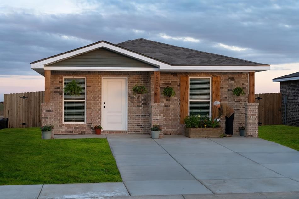 Photo of a retiree planting flowers in a flower box outside a Betenbough Homes Origin Collection floor plan, perfect for aging parents.