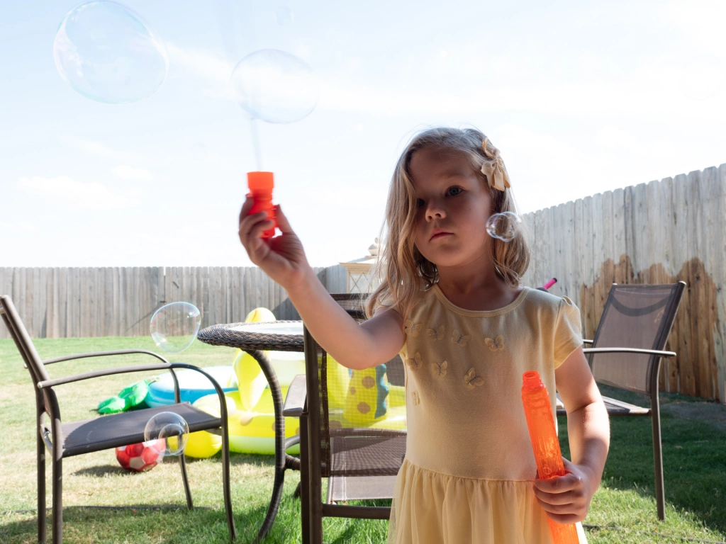 Photo of a child playing with bubbles in a backyard.