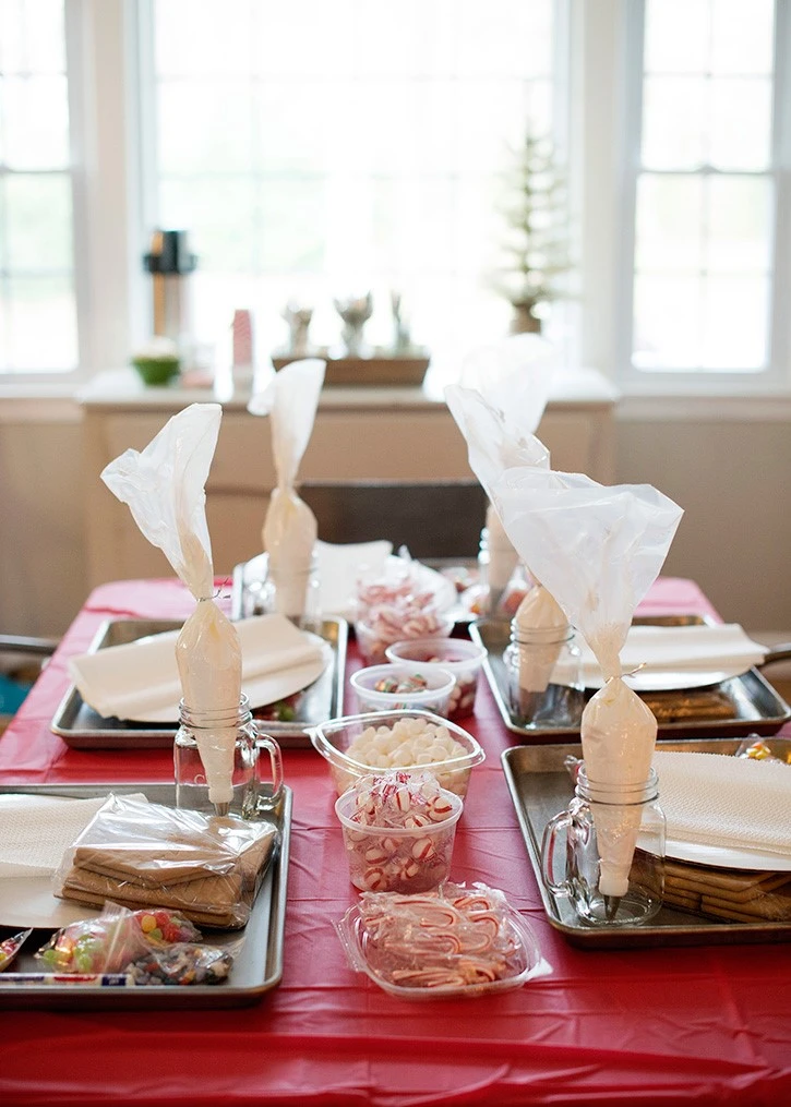 Photo of a gingerbread house station with trays of gingerbread, candies, icing, and marshmallows.