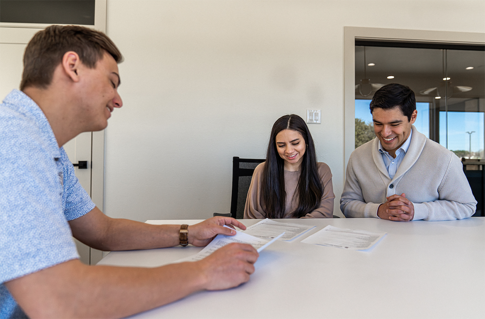 Photo of a Betenbough Homes sales manager reviewing an agreement with home buyers.