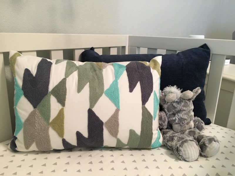 Photo of pillows and a stuffed animal in a twin nursery.