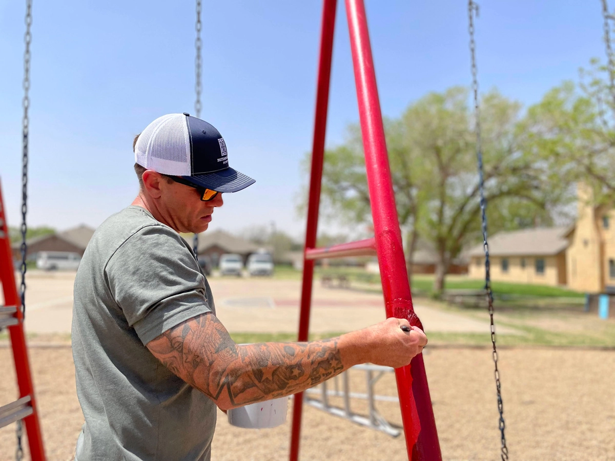 Photo of a Betenbough employee painting playground equipment at a local community center.