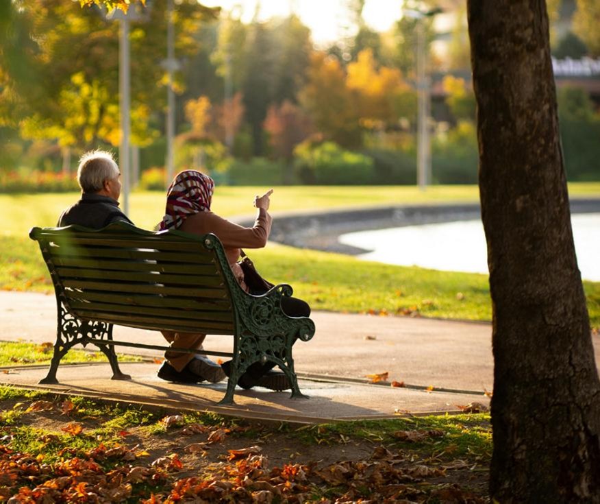 Photo of an elderly couple sitting on a park bench.