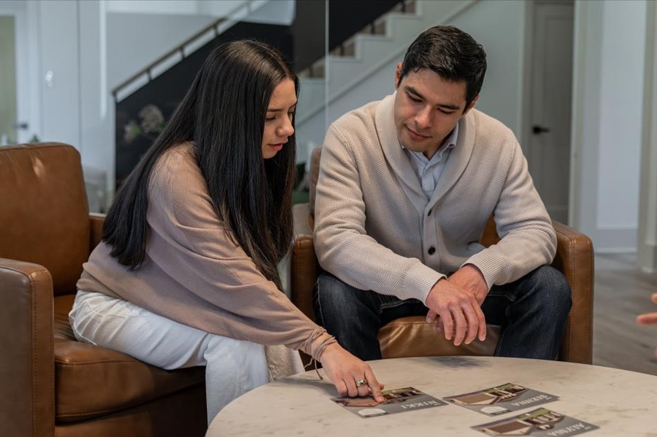 Photo of a couple considering interest rates and looking at different floor plans at a Betenbough Homes New Home Center.