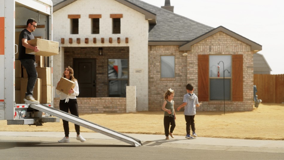 Photo of a family unloading boxes from a moving van in front of their Betenbough home.