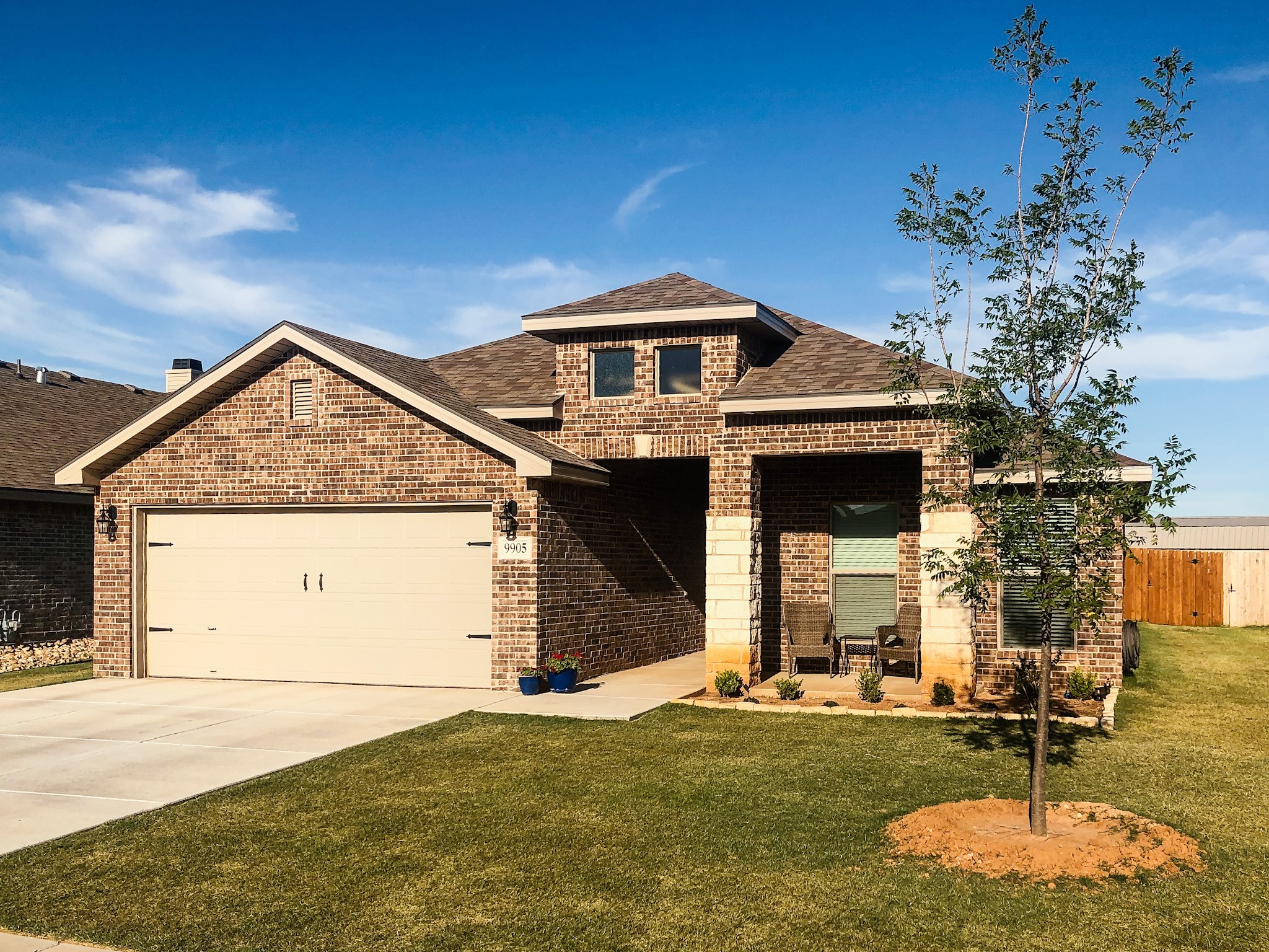 Photo of a Betenbough home with a Bermuda grass front yard. Flower beds and a tree are visible.