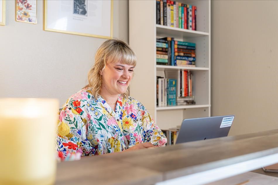 Photo of a woman in a Betenbough home sitting at a desk working on her laptop.