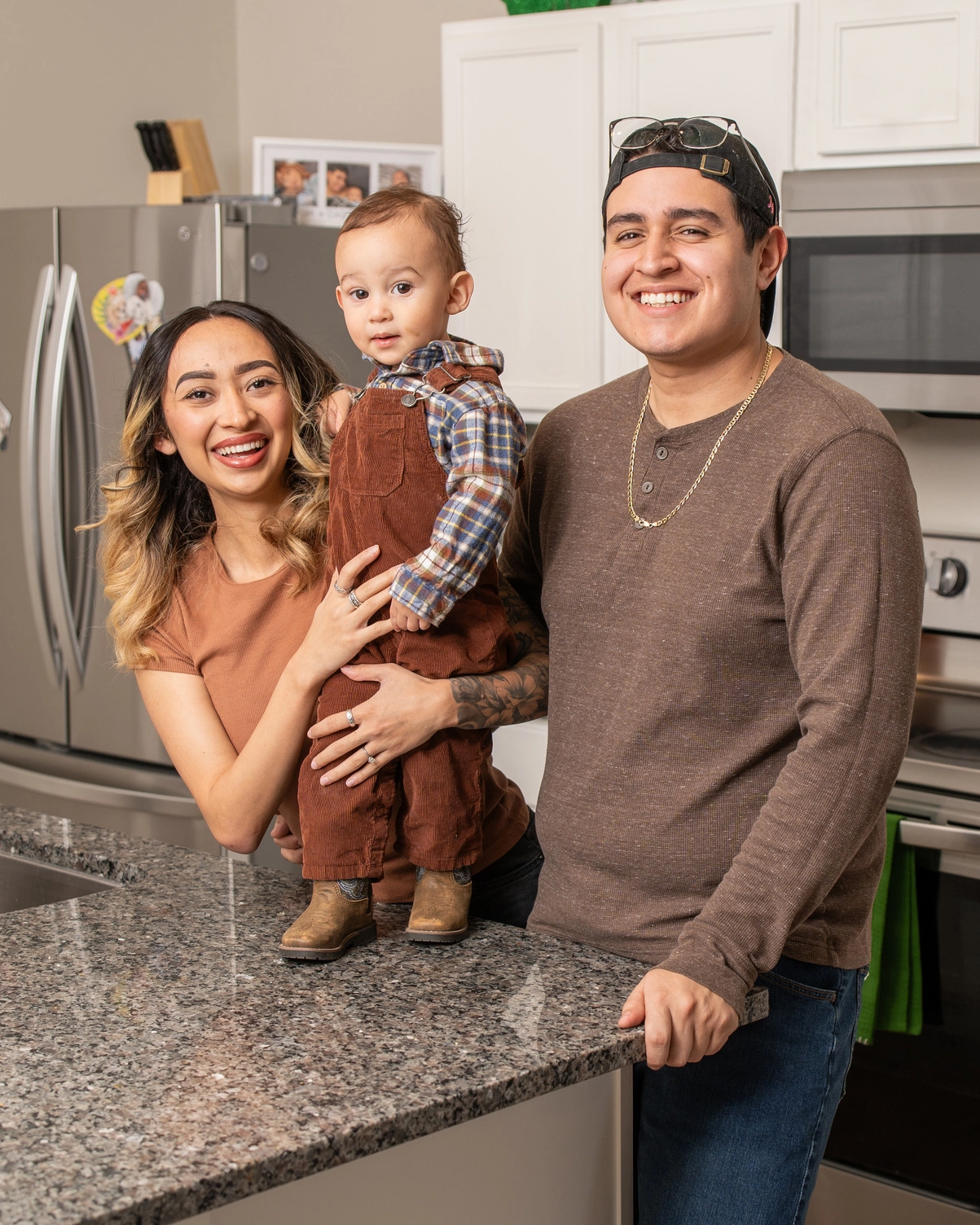 Happy family of three smiling together within their kitchen. 