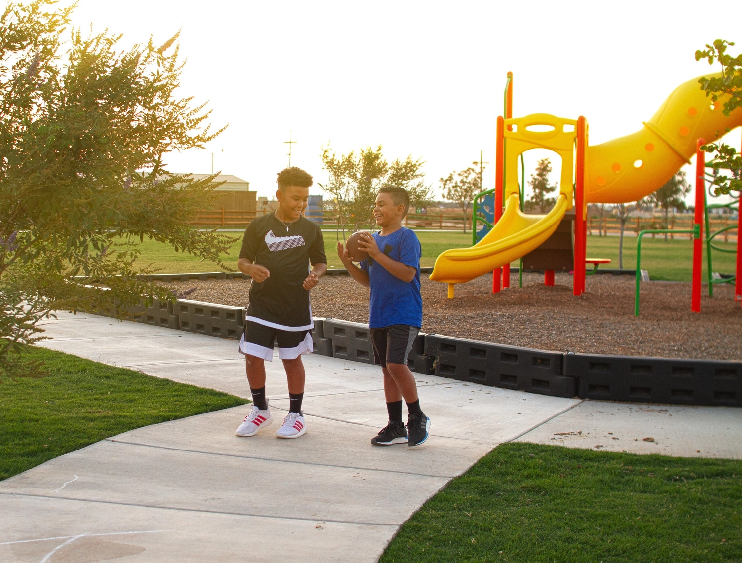 Kids playing with a football by a playground in a Betenbough neighborhood