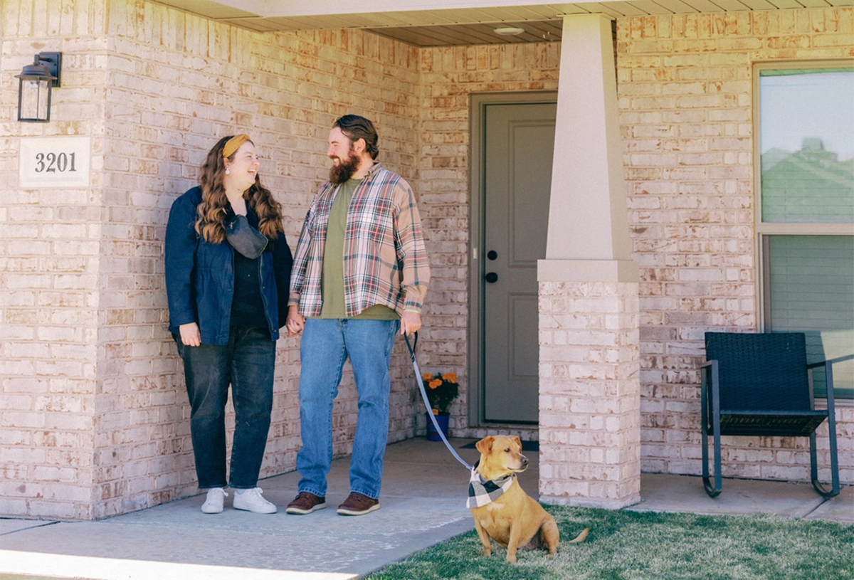 A couple with their dog standing outside the front entrance of their new Betenbough home
